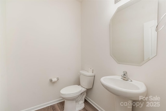 bathroom featuring toilet, sink, and hardwood / wood-style floors