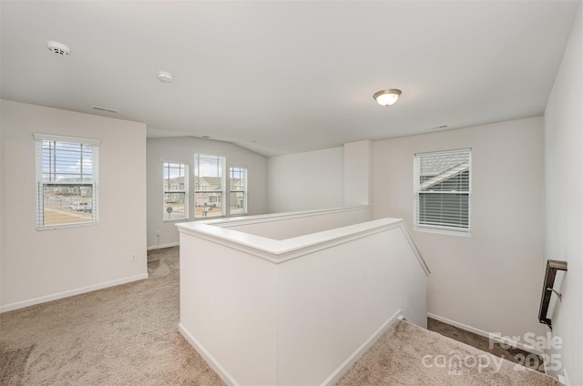 hallway with lofted ceiling and light colored carpet