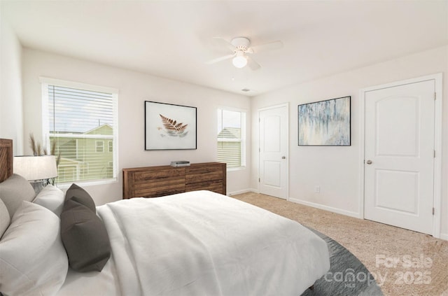 bedroom featuring ceiling fan, multiple windows, and light carpet