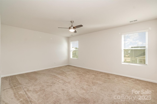 carpeted spare room with ceiling fan and plenty of natural light