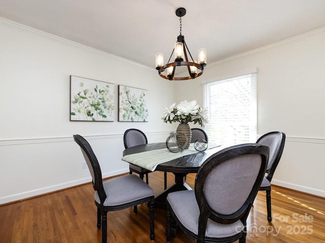 dining room with wood-type flooring, ornamental molding, and an inviting chandelier