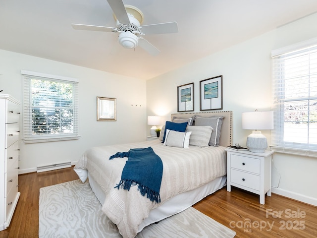 bedroom with wood-type flooring, baseboard heating, and ceiling fan