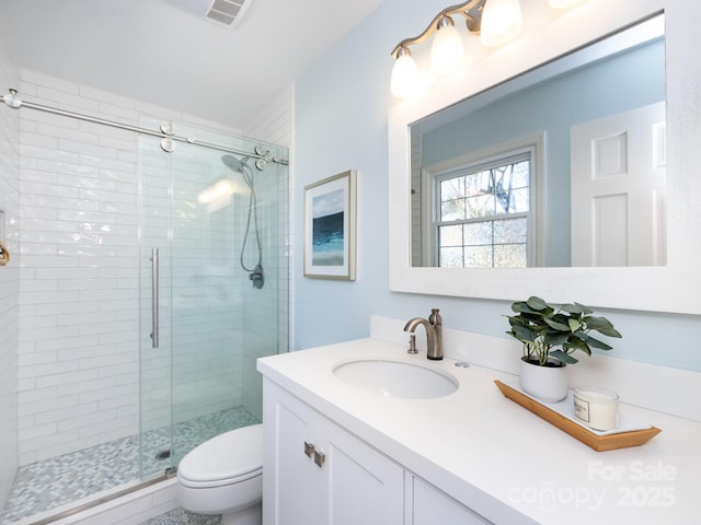 bathroom with vanity, toilet, and a shower with door