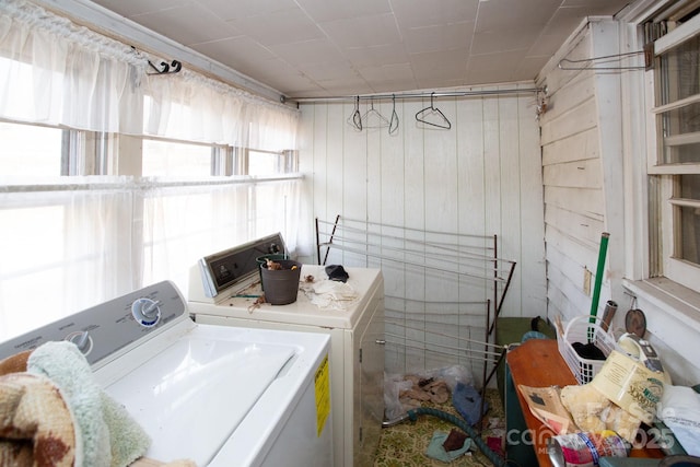 washroom with wood walls and washing machine and clothes dryer