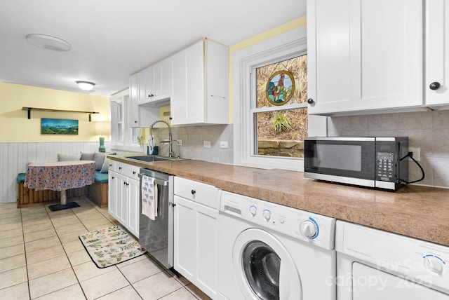 kitchen with dishwasher, white cabinets, light tile patterned flooring, and sink