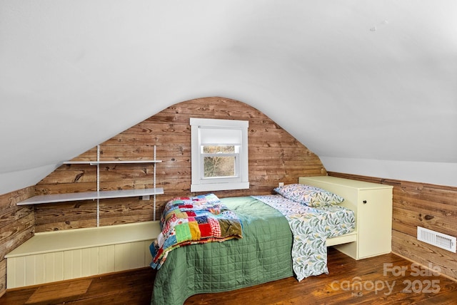 bedroom featuring dark hardwood / wood-style flooring, vaulted ceiling, and wooden walls