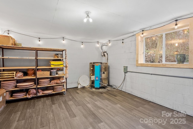 basement with water heater and hardwood / wood-style flooring