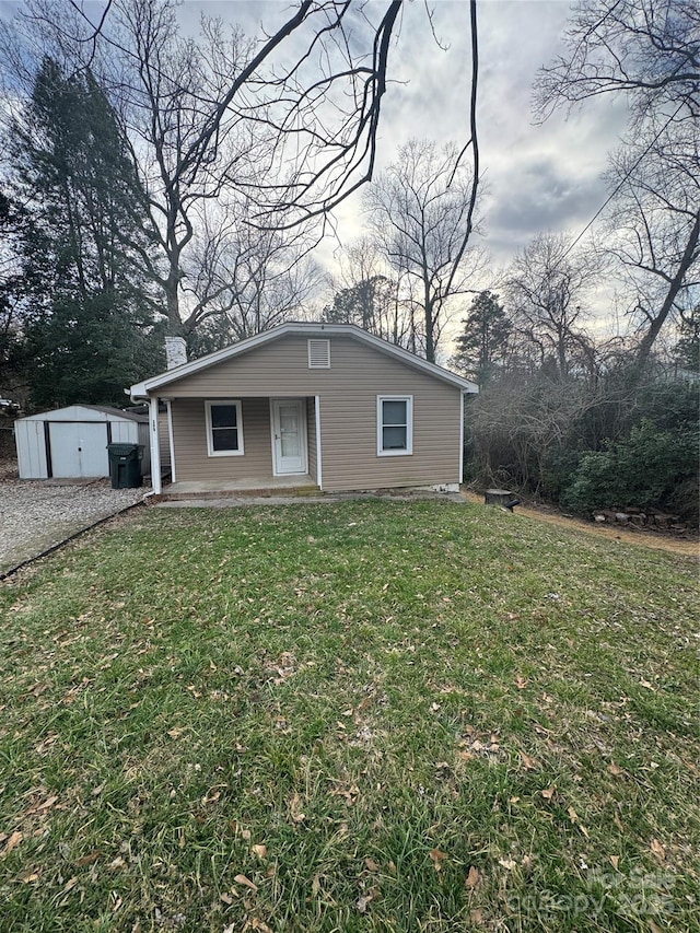 bungalow-style home featuring a porch, a front yard, an outbuilding, and a storage unit