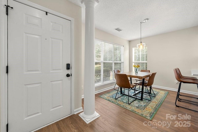 dining space featuring ornate columns, hardwood / wood-style flooring, and a textured ceiling