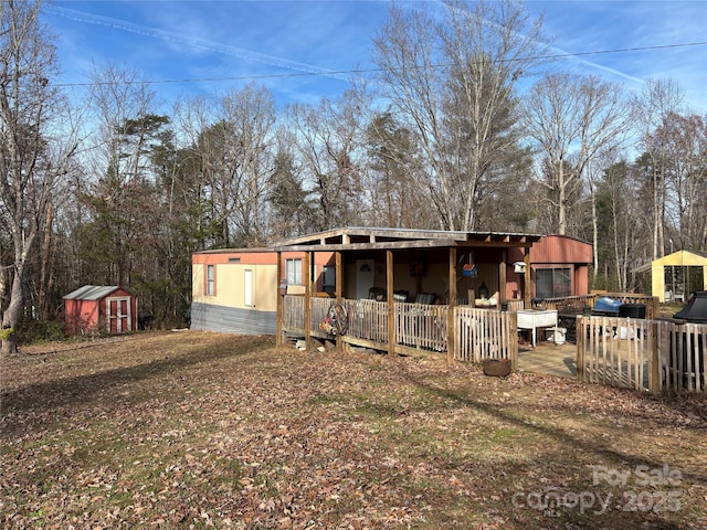 back of house with a storage shed