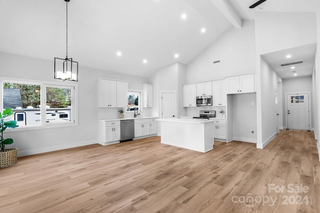 kitchen with white cabinets, light hardwood / wood-style floors, a kitchen island, and appliances with stainless steel finishes