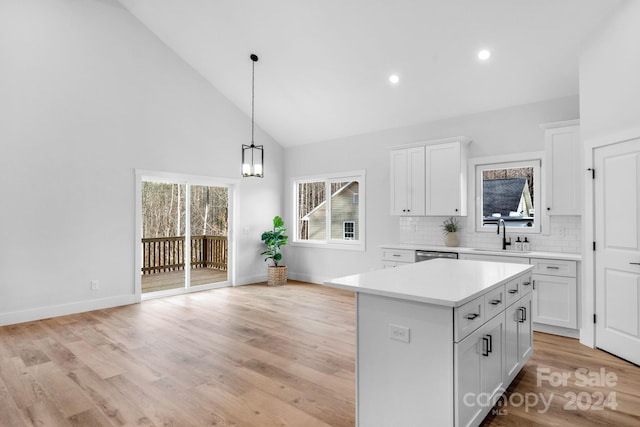 kitchen with white cabinets, a kitchen island, sink, and light hardwood / wood-style flooring