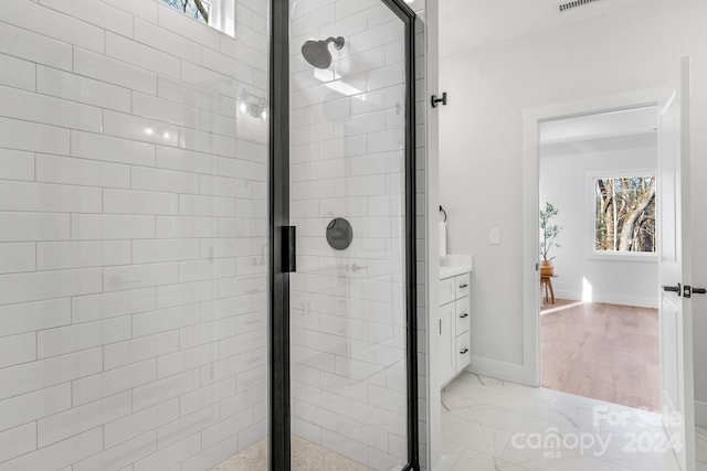 bathroom with hardwood / wood-style floors, vanity, plenty of natural light, and a shower with shower door