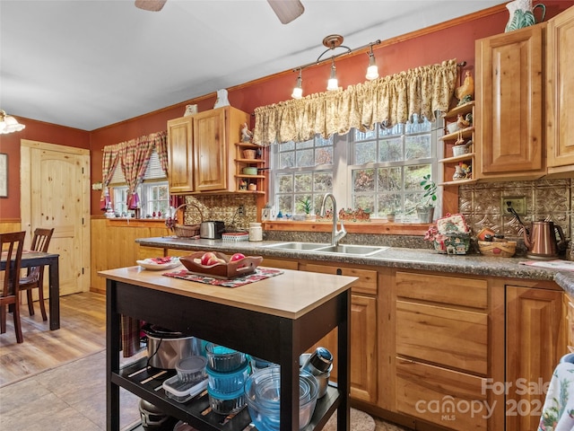 kitchen with ceiling fan, sink, light hardwood / wood-style flooring, wood walls, and decorative backsplash