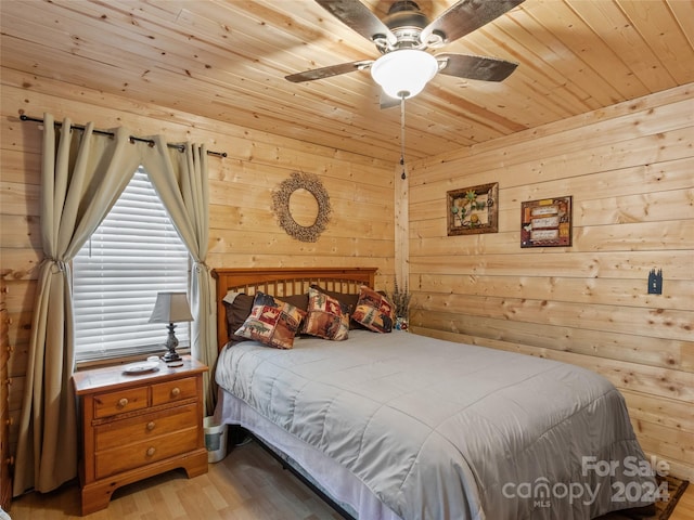 bedroom featuring ceiling fan, wood ceiling, wooden walls, and light hardwood / wood-style flooring