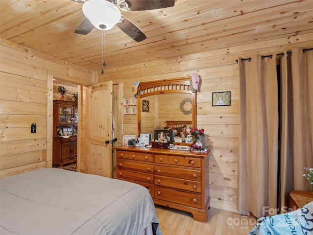 bedroom featuring light wood-type flooring, ceiling fan, and wood walls