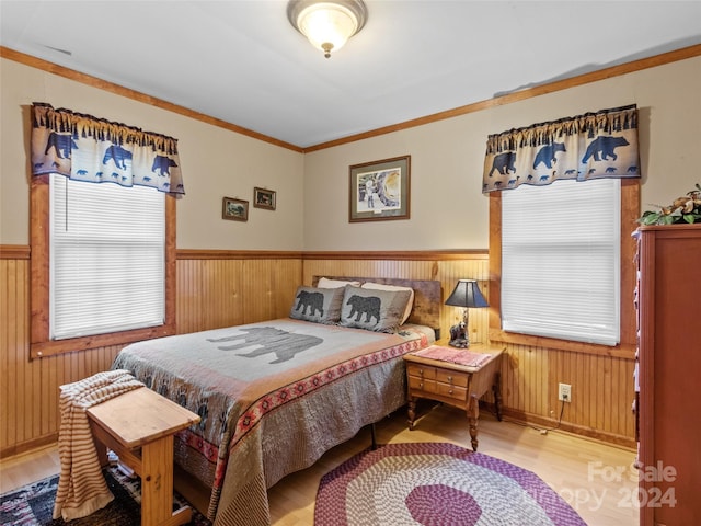 bedroom with light wood-type flooring, wooden walls, and crown molding