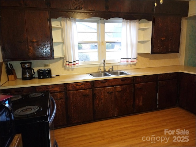 kitchen with light wood-type flooring, black range with electric cooktop, sink, and dark brown cabinetry