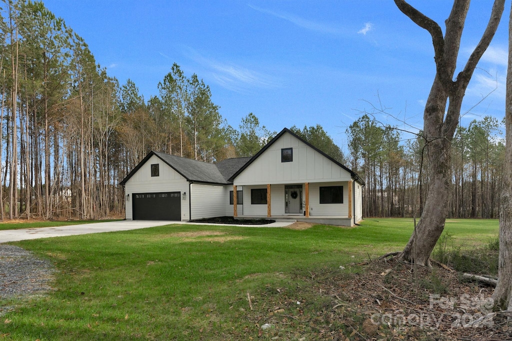 modern farmhouse style home featuring covered porch, a front yard, and a garage