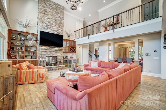 living room with crown molding, a notable chandelier, a fireplace, and light hardwood / wood-style flooring