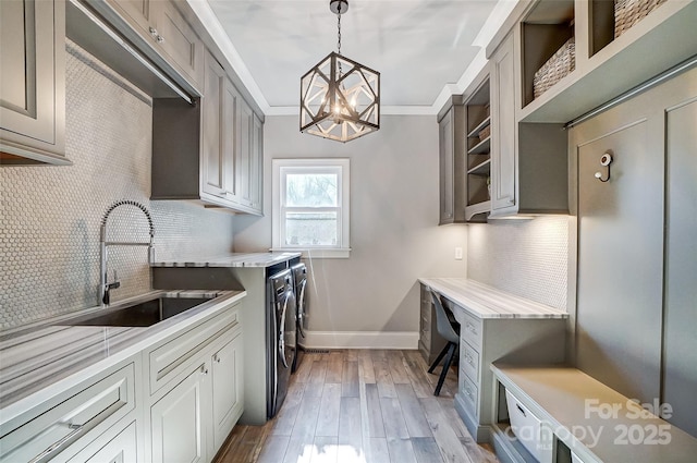 laundry area featuring sink, crown molding, cabinets, hardwood / wood-style flooring, and washing machine and dryer