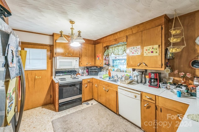 kitchen with white appliances, decorative light fixtures, and sink