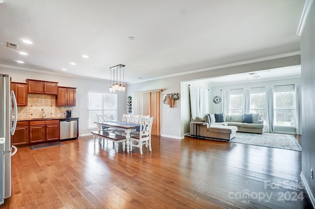 dining area with hardwood / wood-style floors, crown molding, and sink