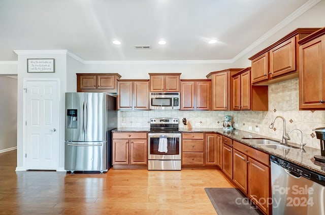 kitchen featuring appliances with stainless steel finishes, sink, backsplash, and dark stone countertops