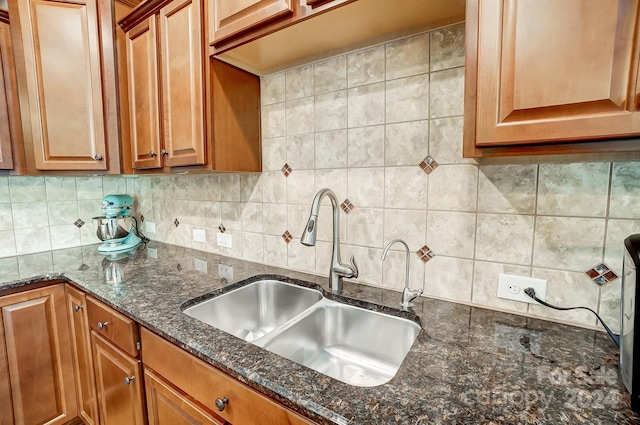 kitchen featuring tasteful backsplash, sink, and dark stone counters