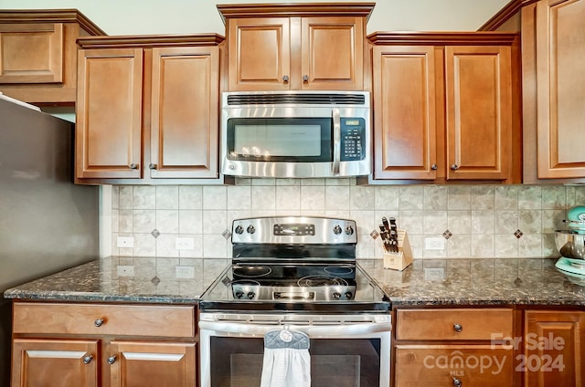 kitchen with tasteful backsplash, dark stone counters, and stainless steel appliances