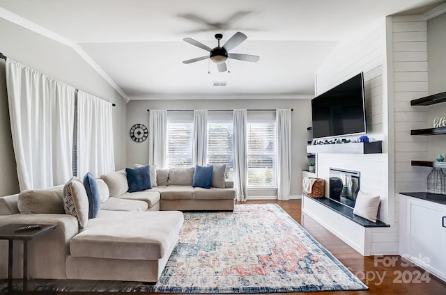 living room with ornamental molding, vaulted ceiling, ceiling fan, dark wood-type flooring, and a fireplace