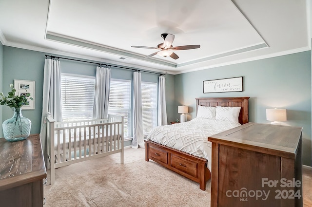 carpeted bedroom with a tray ceiling, ceiling fan, and ornamental molding