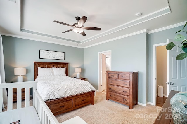 carpeted bedroom with a tray ceiling, ceiling fan, and ornamental molding