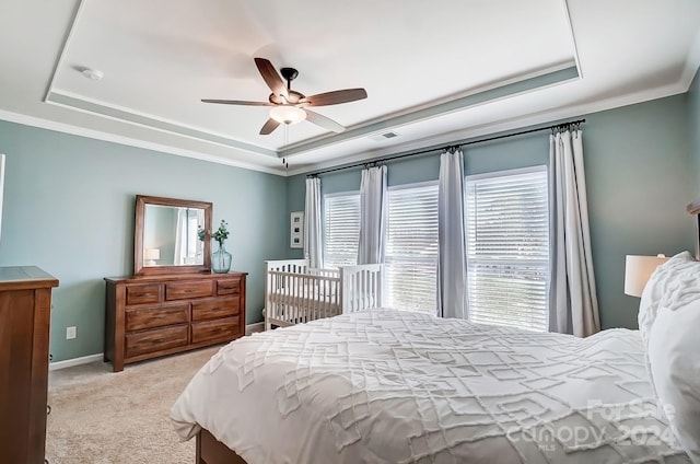 bedroom with a raised ceiling, ceiling fan, crown molding, and light carpet