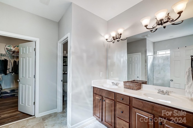 bathroom featuring vanity, a chandelier, a shower with shower door, and toilet