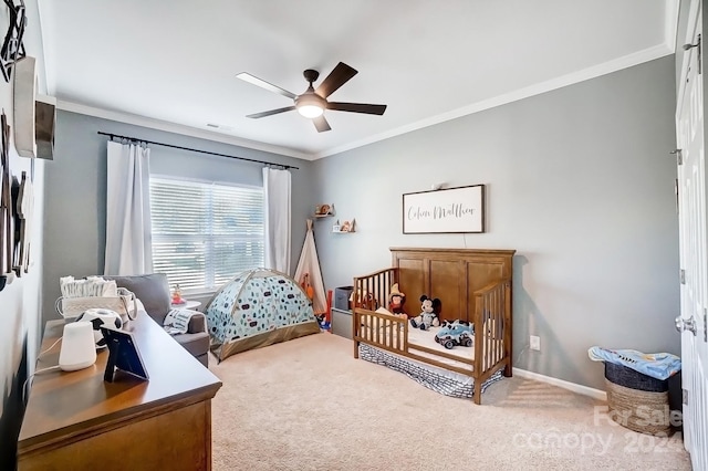 bedroom with carpet flooring, ceiling fan, a crib, and crown molding