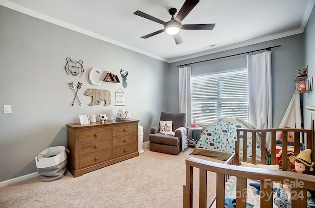 carpeted bedroom with ceiling fan, a crib, and crown molding