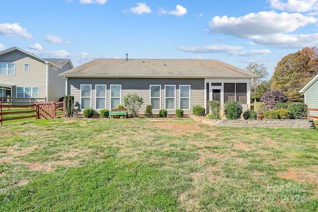 rear view of property featuring a sunroom and a yard