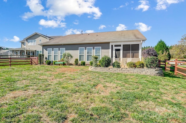 rear view of house with a sunroom and a yard