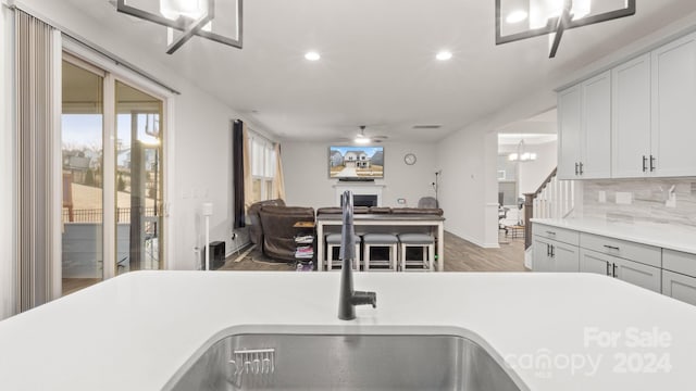 kitchen with decorative backsplash, dark hardwood / wood-style flooring, and ceiling fan with notable chandelier