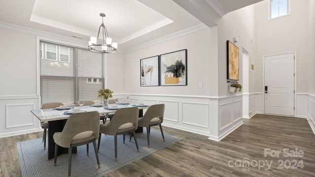 dining space with dark hardwood / wood-style floors, an inviting chandelier, a tray ceiling, and crown molding