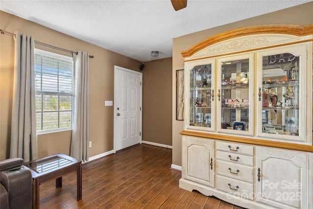 foyer featuring baseboards, dark wood-style flooring, a ceiling fan, and a textured ceiling