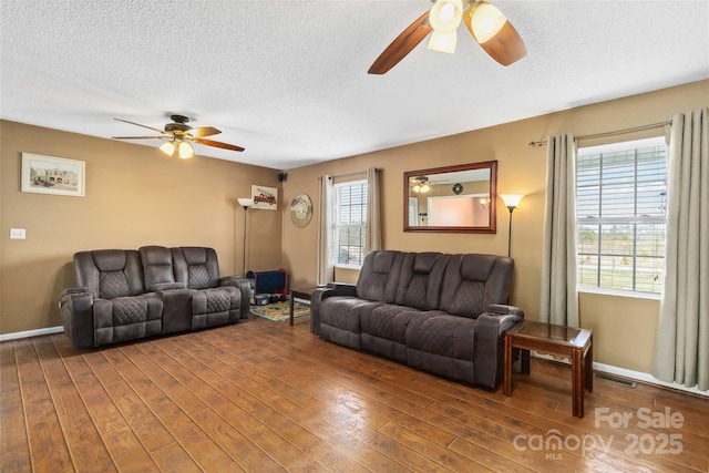 living area featuring ceiling fan, wood finished floors, plenty of natural light, and a textured ceiling