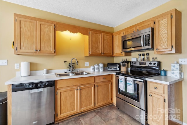 kitchen with stainless steel appliances, a sink, light countertops, and a textured ceiling
