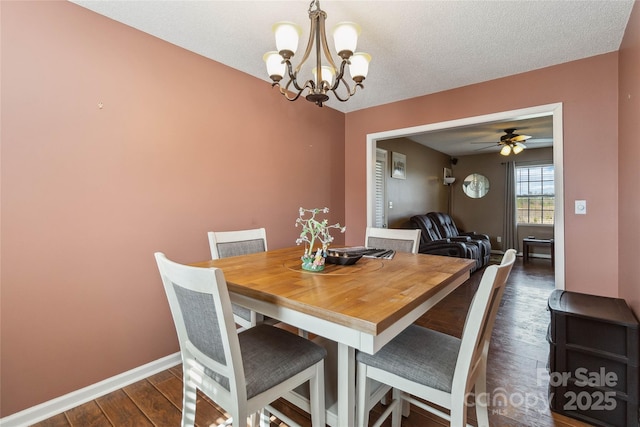 dining area featuring dark wood-type flooring, a chandelier, baseboards, and ceiling fan