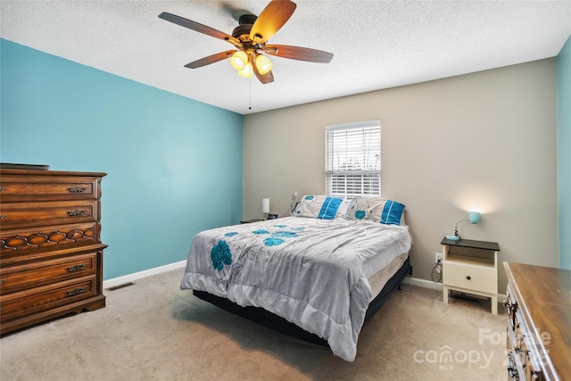 bedroom featuring light carpet, baseboards, a ceiling fan, and a textured ceiling