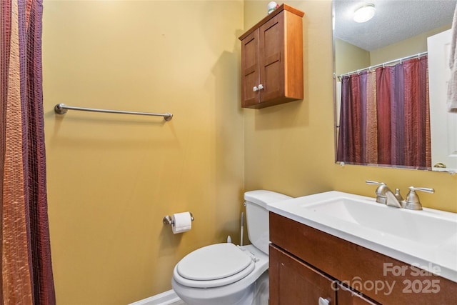 bathroom with toilet, vanity, and a textured ceiling