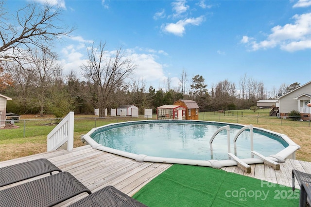 view of swimming pool with a storage unit, a wooden deck, an outdoor structure, and view of scattered trees