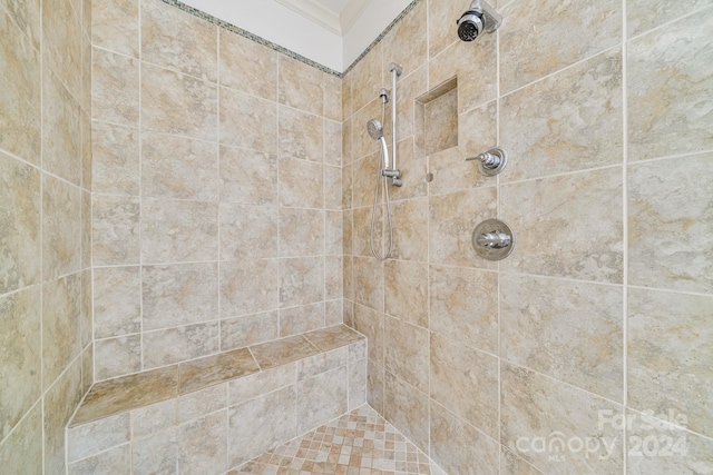 bathroom featuring tiled shower and crown molding