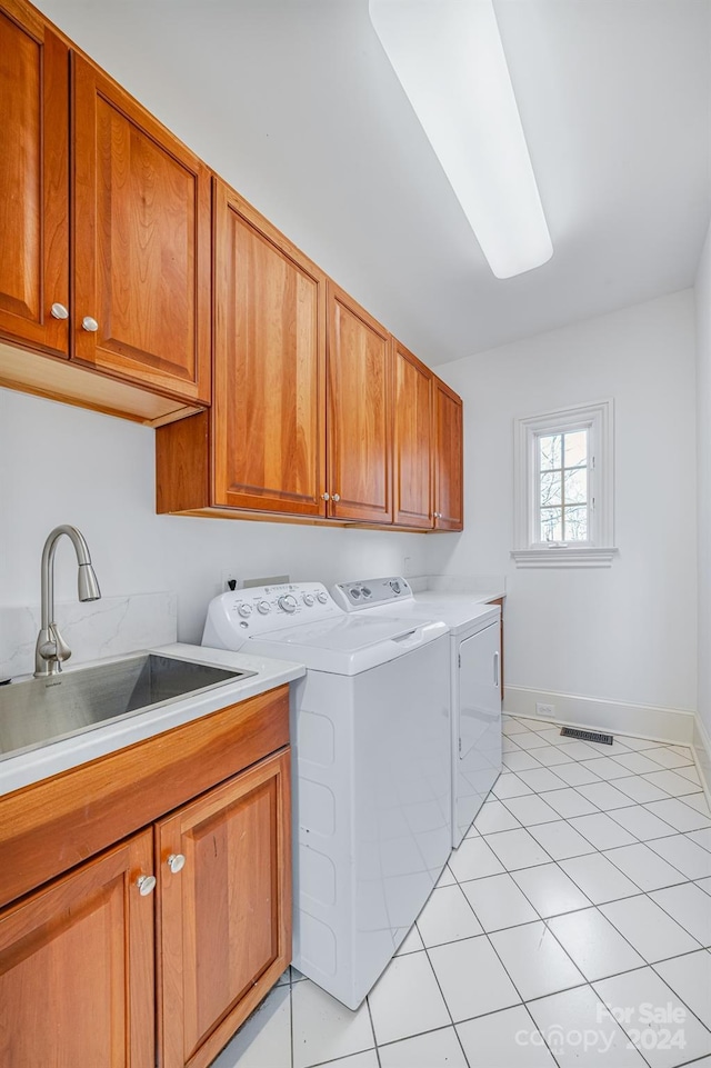 laundry room featuring washing machine and dryer, sink, light tile patterned flooring, and cabinets